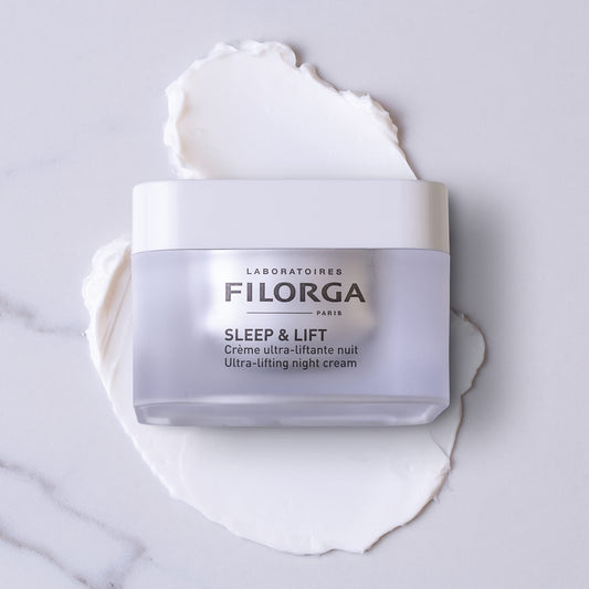 Filorga Sleep & Lift night cream jar on a white cream-texture background